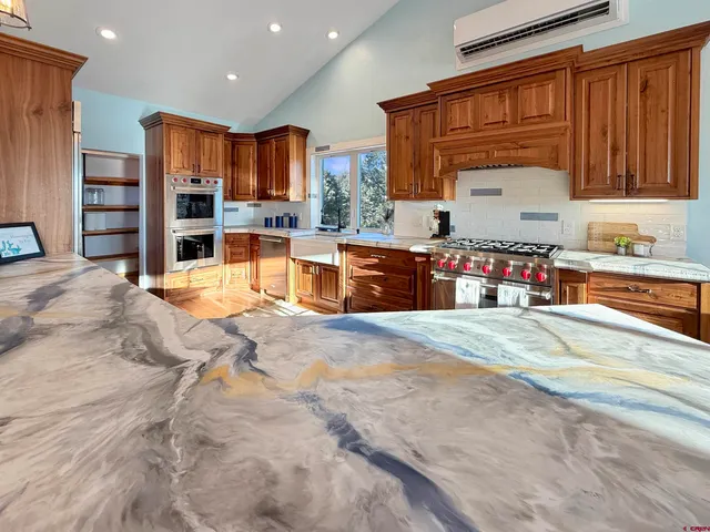 a large kitchen with stainless steel appliances granite countertop a stove refrigerator and cabinets