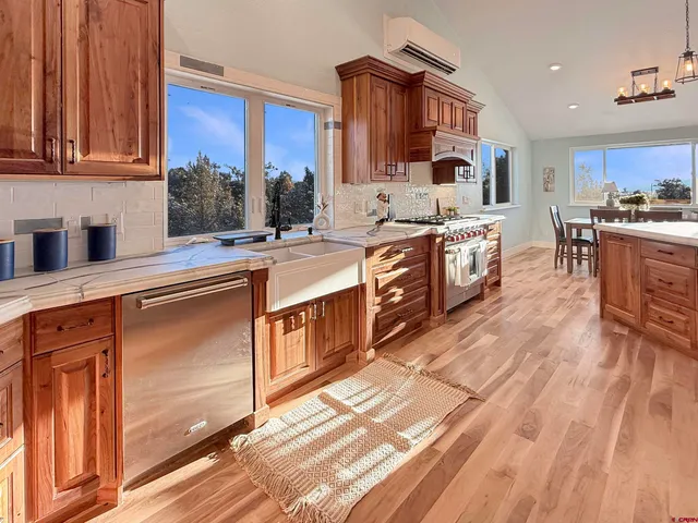 a large kitchen with stainless steel appliances granite countertop a stove a sink dishwasher and cabinets with wooden floor