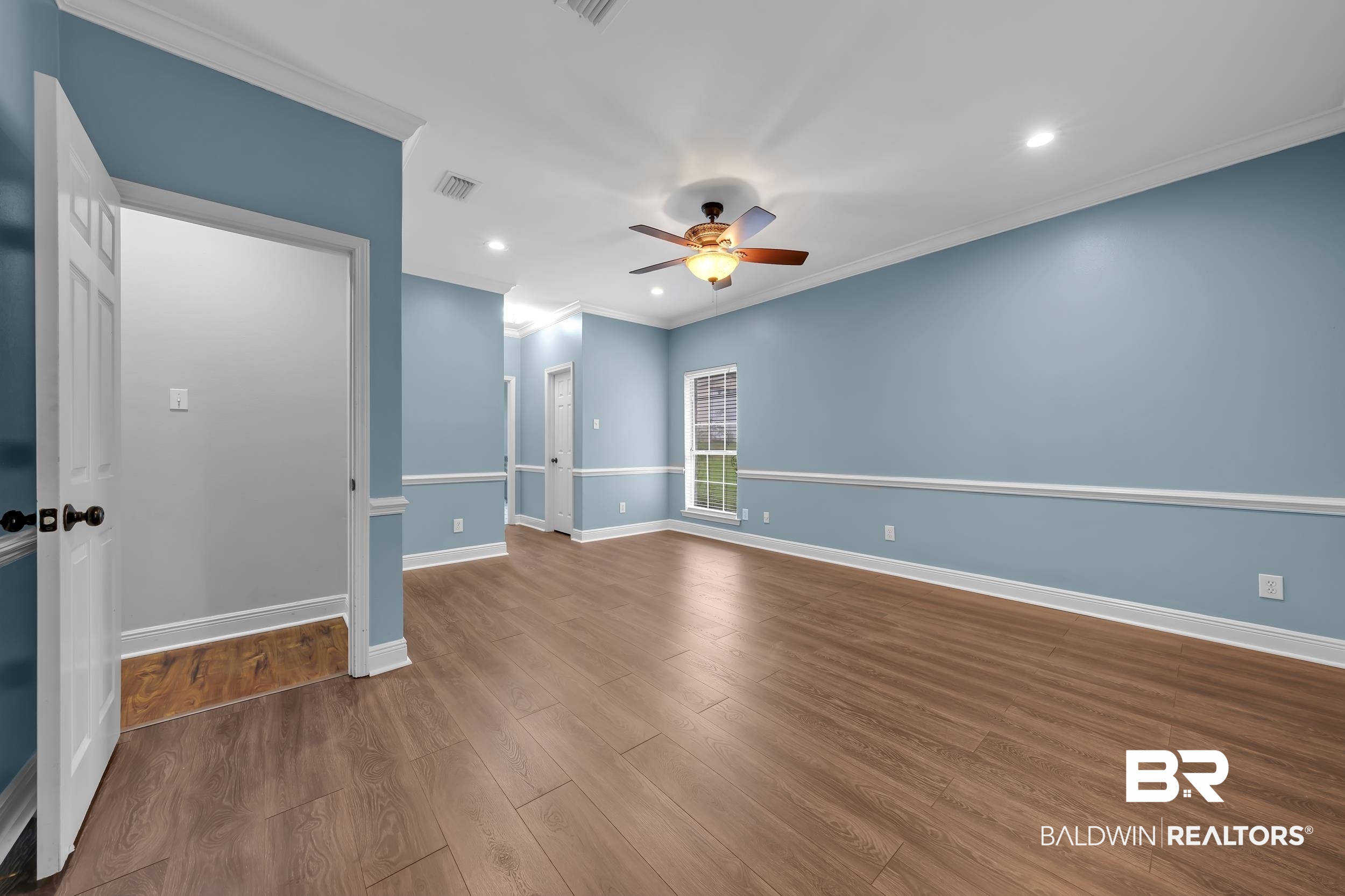 14960 Howells Ferry Road Wilmer, AL 36587 - Photo 11 of 22 Spacious room featuring wood-finish flooring, light blue walls with chair rail molding, and white trim