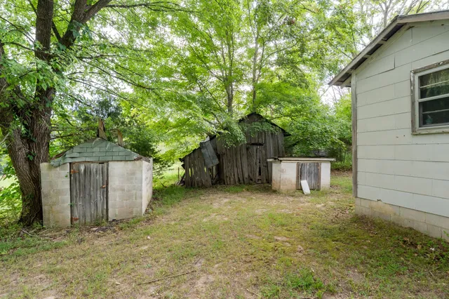 a backyard of a house with plants and tree with wooden fence