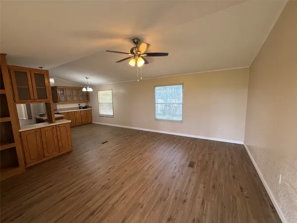 a view of an empty room with a window and wooden floor