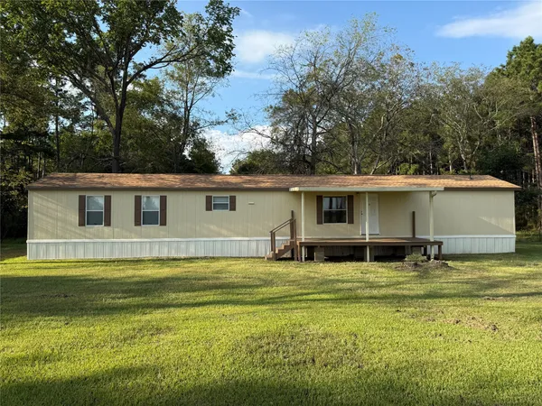a front view of house with yard and trees in the background