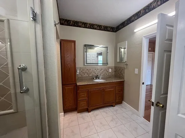 a bathroom with a granite countertop sink mirror and a bathtub