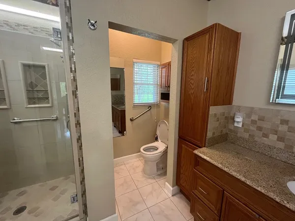 a bathroom with a granite countertop toilet a sink and a shower
