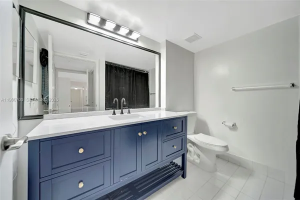 a bathroom with a toilet a double vanity sink and a mirror