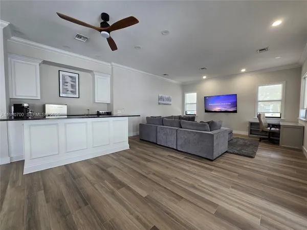 a living room with furniture kitchen view and a wooden floor