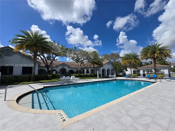a view of swimming pool that has lawn chairs and a dining table under an umbrella