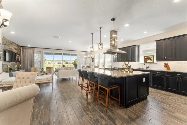a kitchen with stainless steel appliances granite countertop a sink a stove and a wooden floors