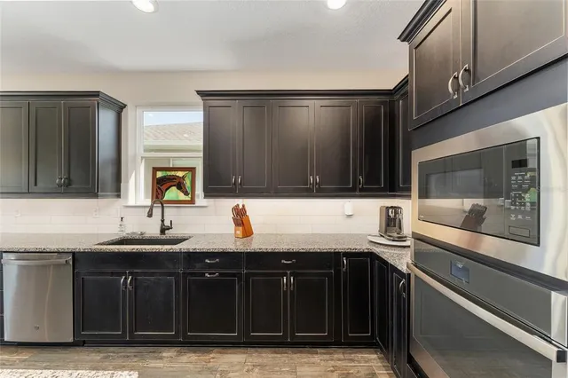 a kitchen with stainless steel appliances granite countertop lots of counter top and wooden floors