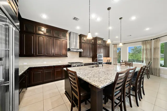 a kitchen with granite countertop a stove a sink a kitchen island a table and chairs