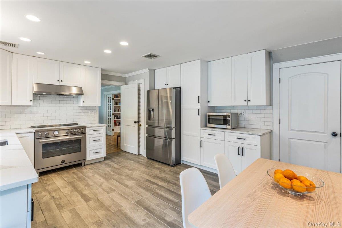130 Sands Point Road Sands Point, NY 11050 - Photo 14 of 26 Kitchen with stainless steel appliances, under cabinet range hood, tasteful backsplash, white cabinetry, and recessed lighting