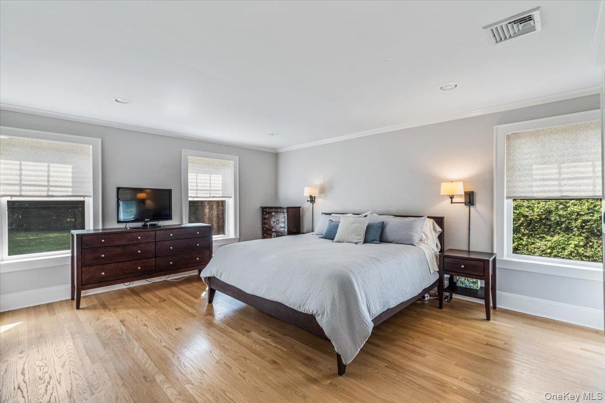 130 Sands Point Road Sands Point, NY 11050 - Photo 19 of 26 Bedroom featuring crown molding, baseboards, multiple windows, and light wood-style floors