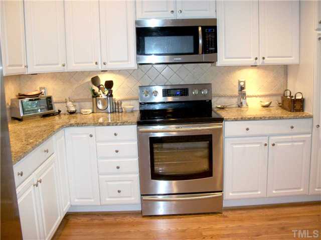 5209 Coffee Tree Drive Raleigh, NC 27613 - Photo 5 of 25 a kitchen with white cabinets and stainless steel appliances