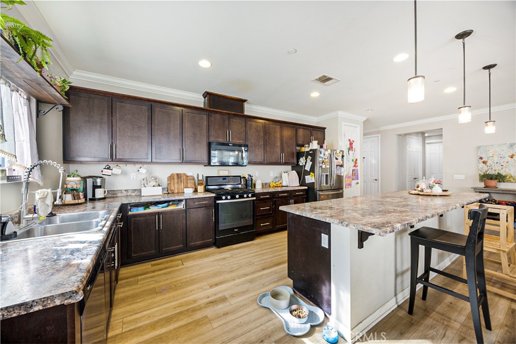 20668 Pitchfork Drive Riverside, CA 92507 - Photo 11 of 25 a kitchen with granite countertop a stove top oven a sink dishwasher a dining table and chairs with wooden floor