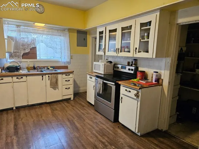 a kitchen view with wooden floor and a living room