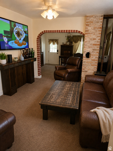 1225 South Main Street Mapleton, UT 84664 - Photo 11 of 13 Living room featuring a carpeted floor, brick-lined arched doorway, brick accent wall, and a ceiling fan with light fixture