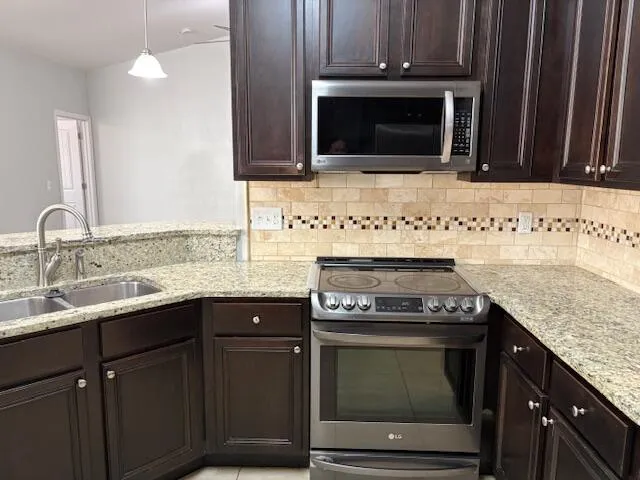 a kitchen with granite countertop a stove top oven microwave and cabinets