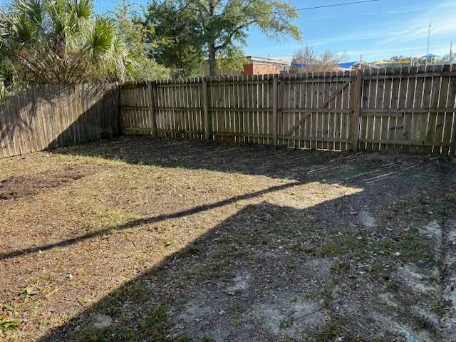 a view of small yard in front of house with wooden fence