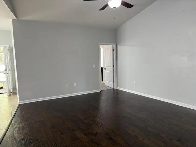 an empty room with wooden floor chandelier fan and windows