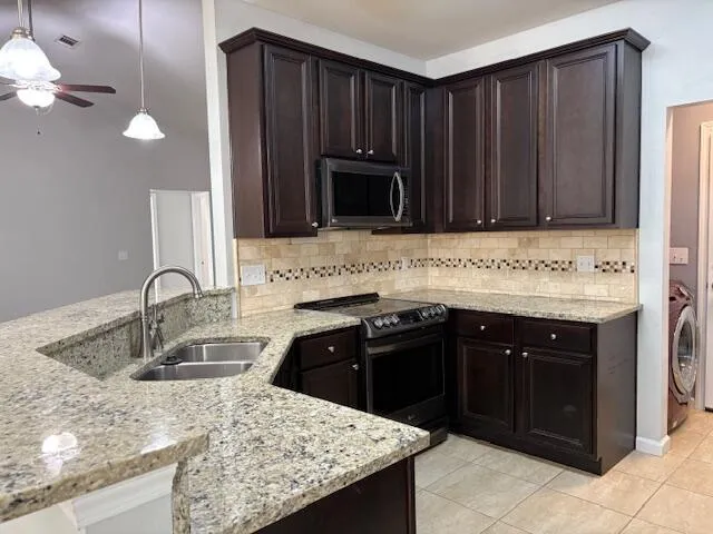 a kitchen with granite countertop a sink and a stove top oven with wooden cabinets