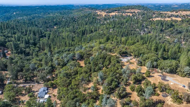 an aerial view of residential houses with outdoor space and trees