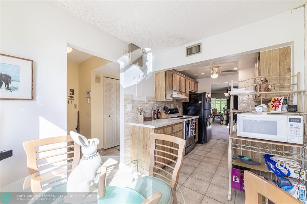 8305 Northwest 61st Street, Unit C215 Tamarac, FL 33321 - Photo 17 of 28 a kitchen with stainless steel appliances kitchen island granite countertop a table and chairs in it