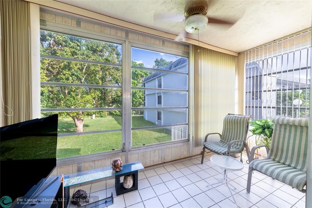 8305 Northwest 61st Street, Unit C215 Tamarac, FL 33321 - Photo 26 of 28 a living room with patio furniture and a floor to ceiling window