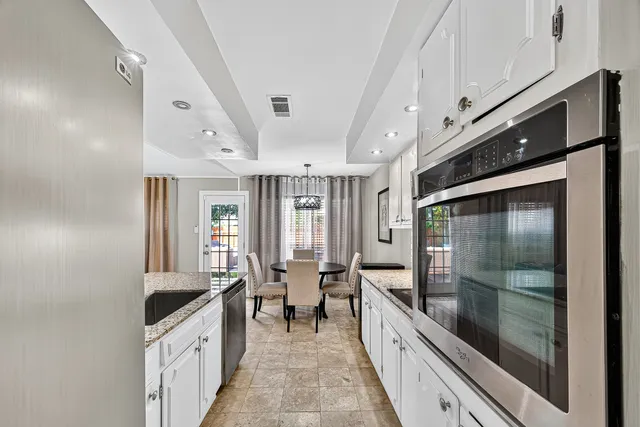 a large white kitchen with granite countertop a large window and white stainless steel appliances