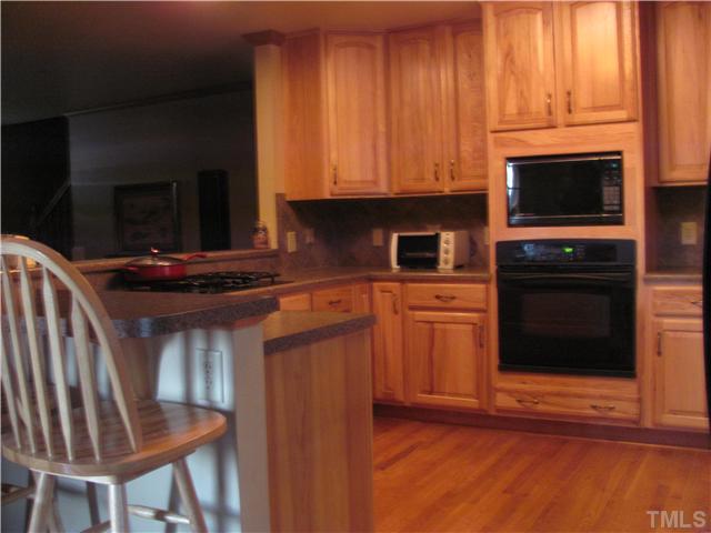 301 Pilot-Riley Road Zebulon, NC 27597 - Photo 7 of 15 a kitchen with stainless steel appliances wooden cabinets and a stove top oven