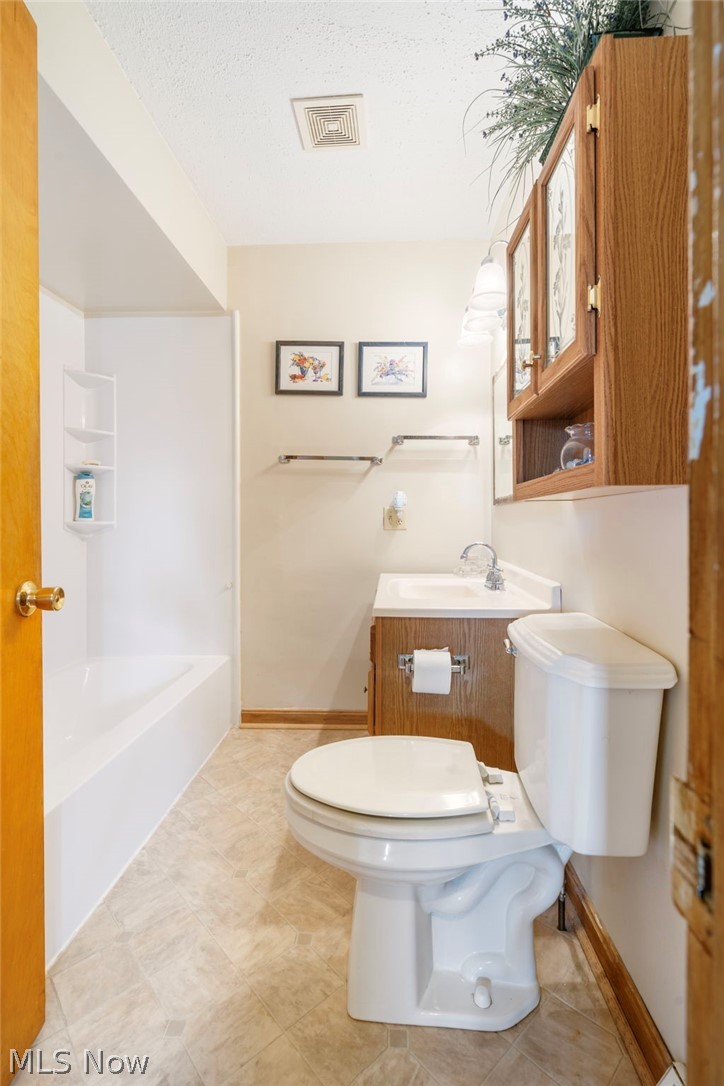 1850 South Sawburg Road Alliance, OH 44601 - Photo 18 of 39 hall Bathroom on first floor with a textured ceiling, tile flooring, toilet, vanity and shower/tub combination