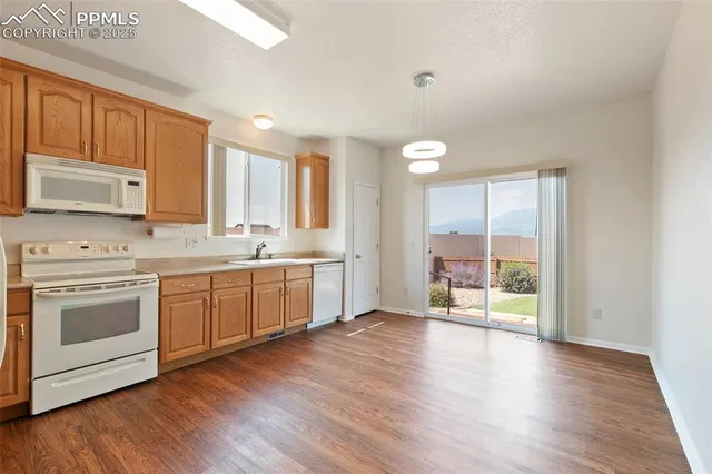 a kitchen with stainless steel appliances granite countertop a refrigerator a sink dishwasher a stove with wooden floors and cabinets