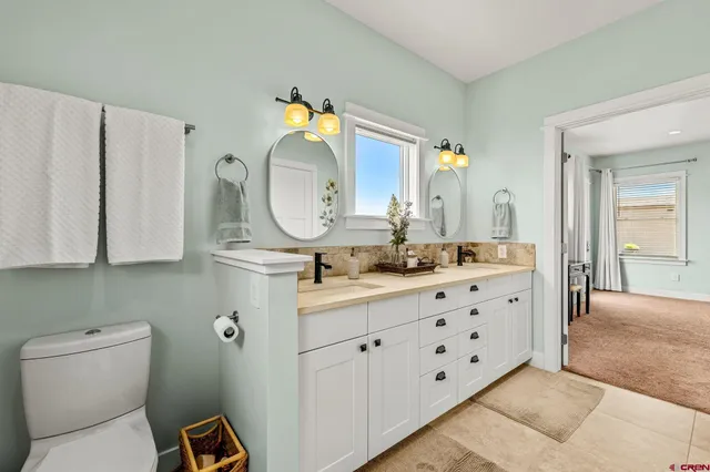 a bathroom with a double vanity sink mirror and toilet