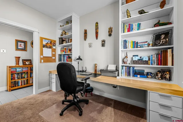 a view of a workspace with bookshelf and a window