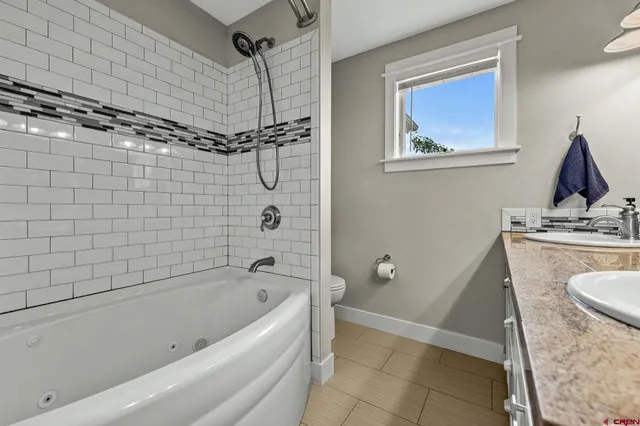 a bathroom with a granite countertop sink a toilet and shower