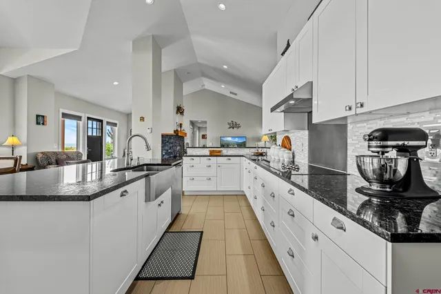 a large white kitchen with stainless steel appliances granite countertop lots of counter space and a sink