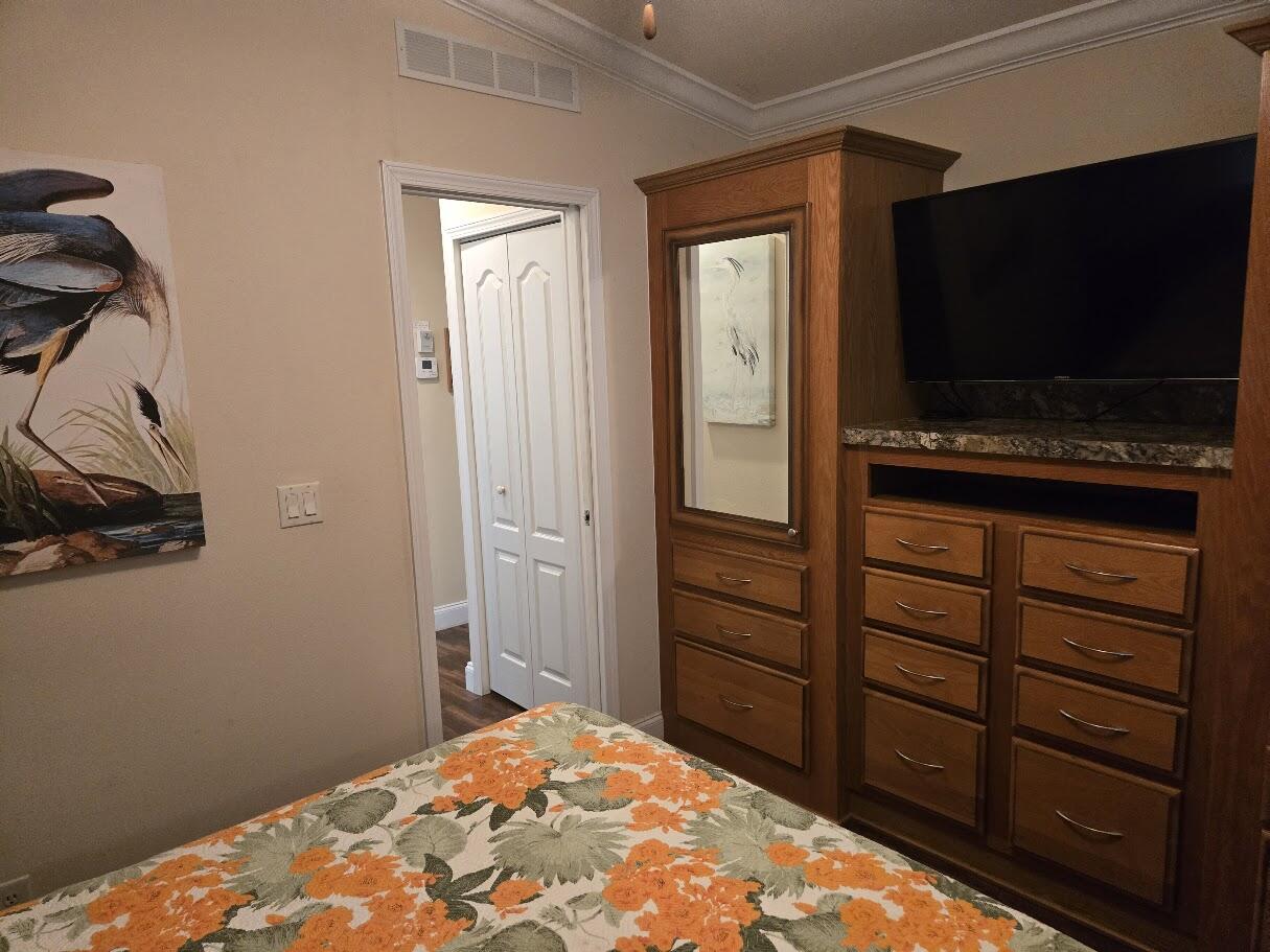 13680 Northwest 127th Terrace, Unit 17 Okeechobee, FL 34974 - Photo 28 of 30 a bedroom with a bed and a flat screen tv