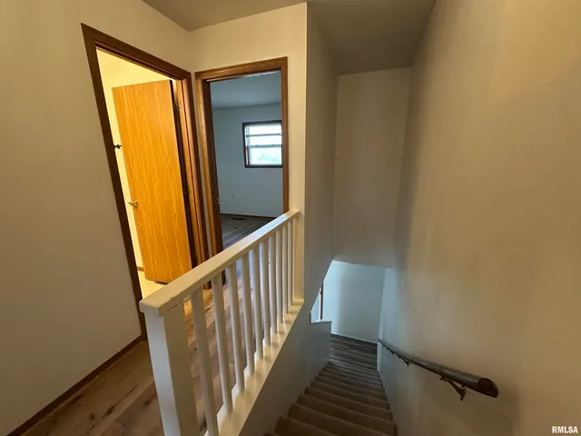 a view of a hallway with wooden floor and stairs