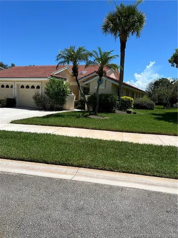 a front view of a house with a yard and palm trees