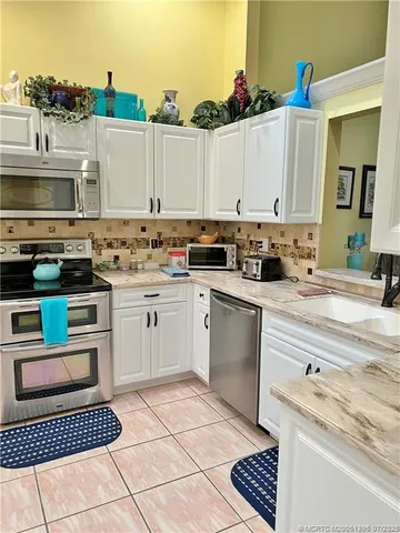 a kitchen with stainless steel appliances kitchen island granite countertop a table chairs in it and wooden floors