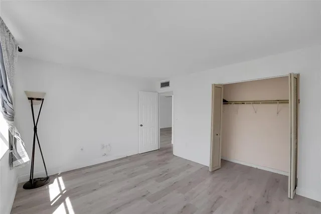 a view of an empty room with wooden floor and a glass door