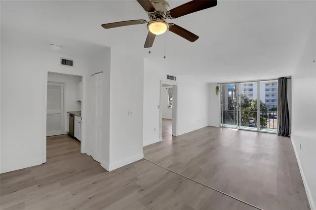 a view of an empty room with window and wooden floor