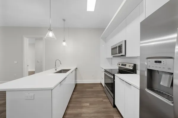 a kitchen with stainless steel appliances a stove top oven a sink a microwave and wooden floors