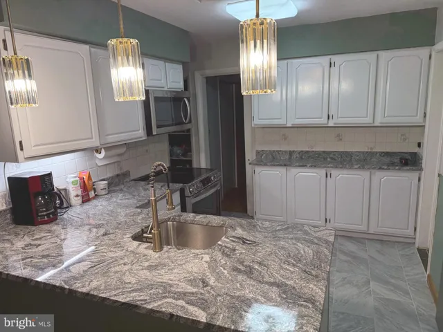 a kitchen with granite countertop a sink stainless steel appliances and cabinets