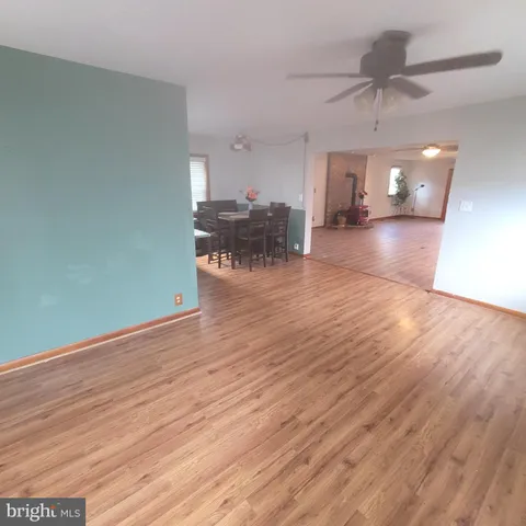 a view of a big room with wooden floor a ceiling fan and staircase