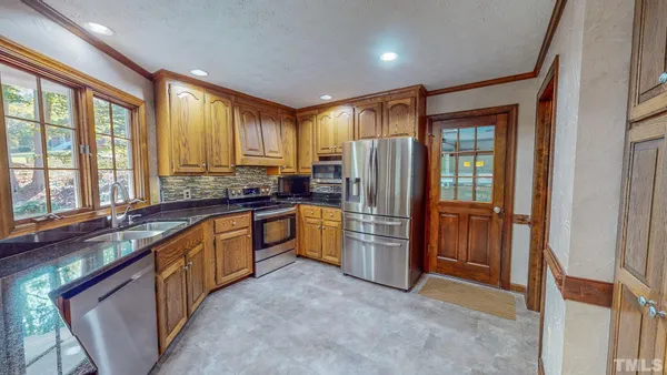 a kitchen with stainless steel appliances granite countertop a refrigerator and a sink