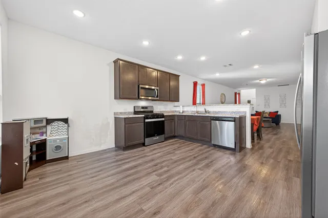 a kitchen with kitchen island stainless steel appliances cabinets and wooden floor