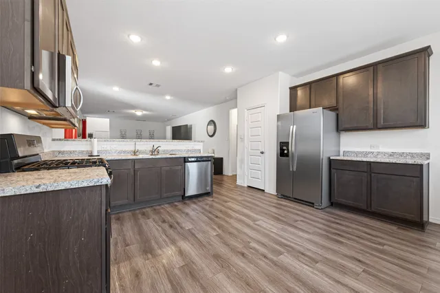 a kitchen with stainless steel appliances a refrigerator a sink a stove a microwave and cabinets