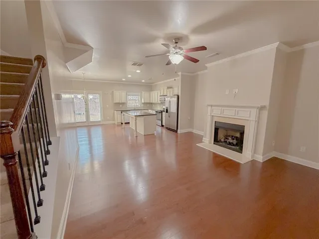 a view of a livingroom with wooden floor and a kitchen