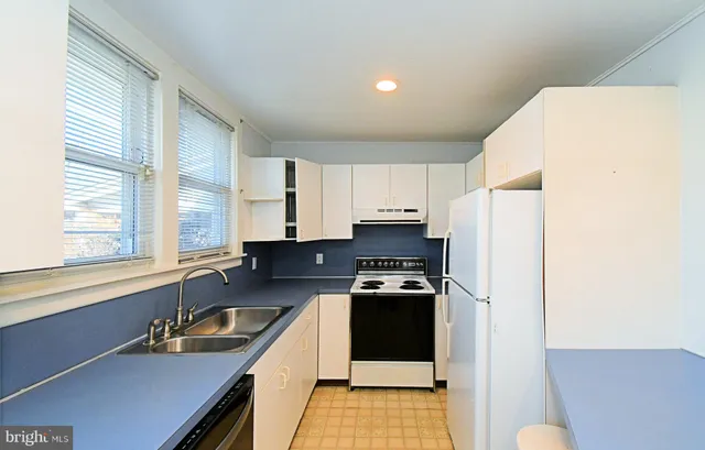 a kitchen with stainless steel appliances a sink a stove a refrigerator and cabinets