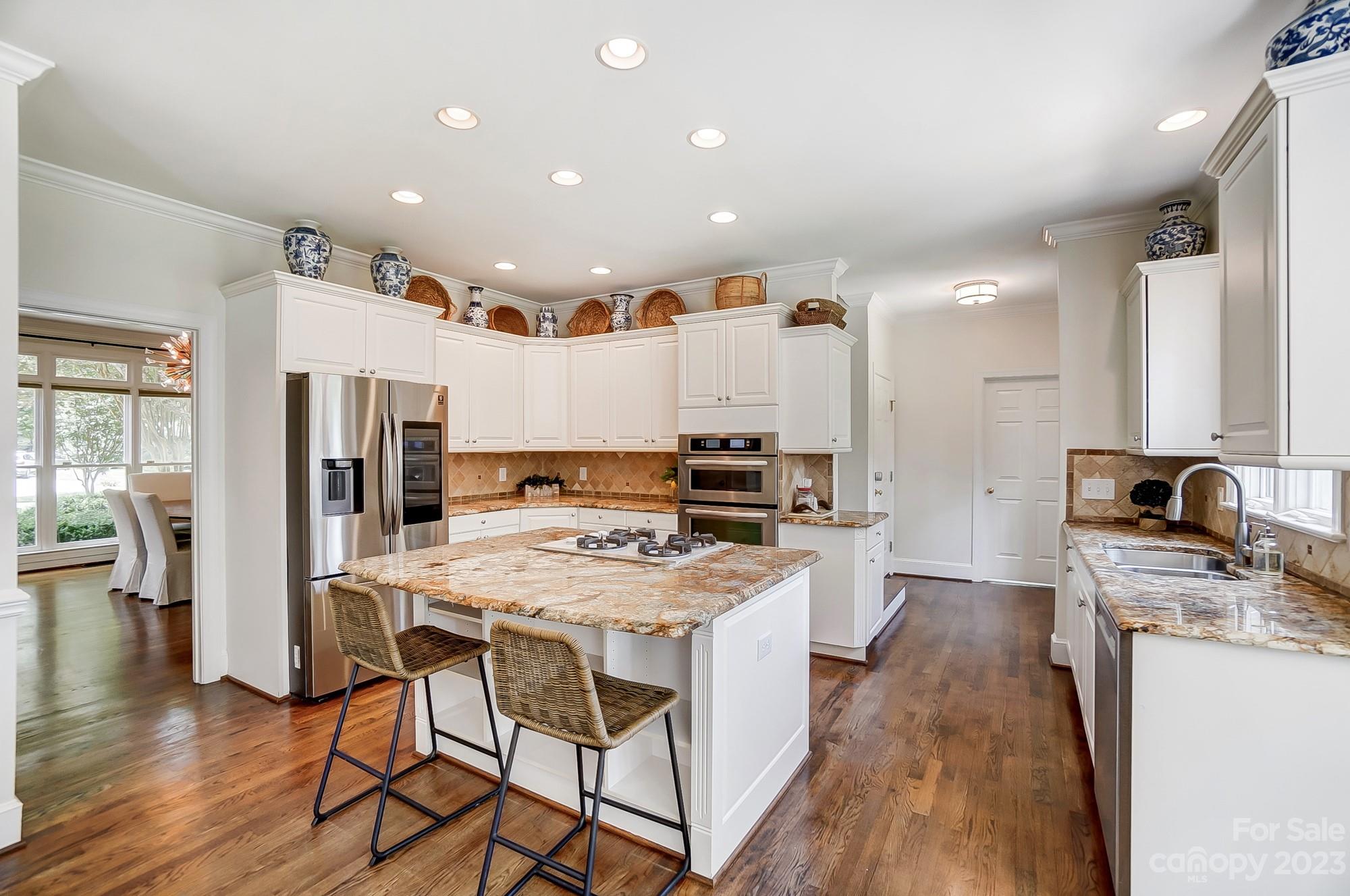 2407 Queensland Drive Charlotte, NC 28270 - Photo 8 of 42 a kitchen with stainless steel appliances granite countertop a stove top oven a refrigerator a sink and a dining table with wooden floor